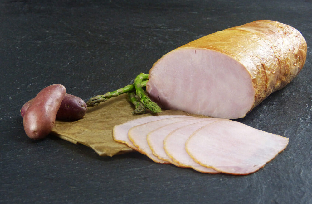 Kasseler ohne Knochen gekocht geschnitten mit roter Kartoffel und grünem Spargel auf Schieferhintergrund