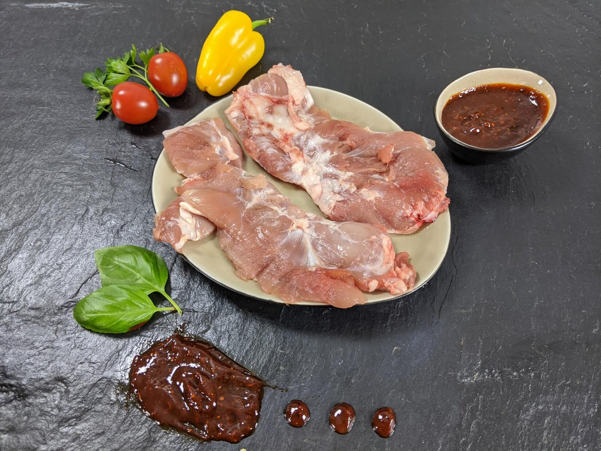 Spider Steak Kachelfleisch Barbecue auf Teller angerichtet mit einer Schale Marinade Tomaten Paprika und Kräutern auf Schieferhintergrund