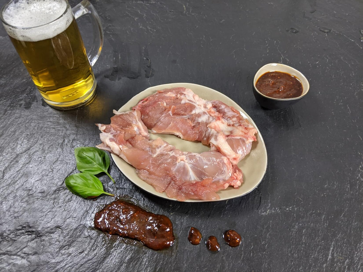 Spider Steak Kachelfleisch Braumeister auf Teller angerichtet mit einer Schale Marinade Kräutern und einem Glas Bier auf Schieferhintergrund