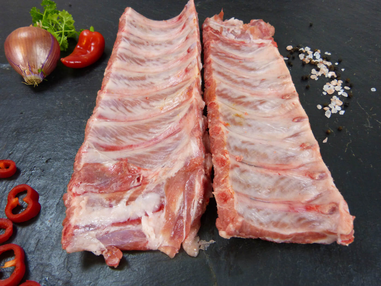 Zwei Schweinekotelettrippchen mit Paprika Zwiebel und grobem Salz auf Schieferhintergrund