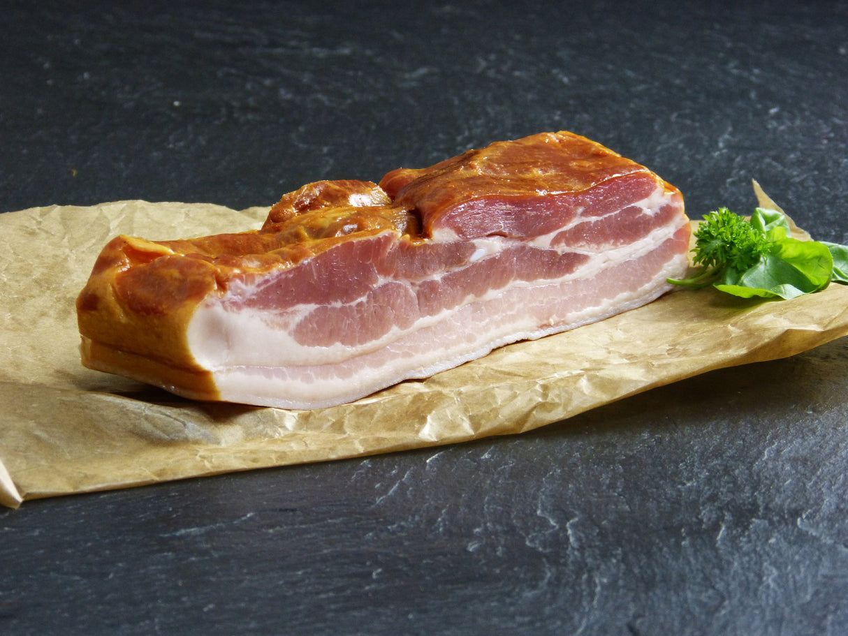 Dörrfleisch vom EIFEL Schwein auf Backpapier mit Kräutern auf Schieferhintergrund