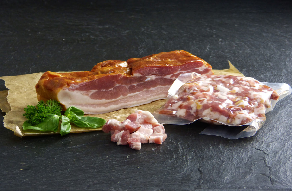 Dörrfleisch gewürfelt mager angerichtet auf Backpapier mit Kräutern auf Schieferhintergrund