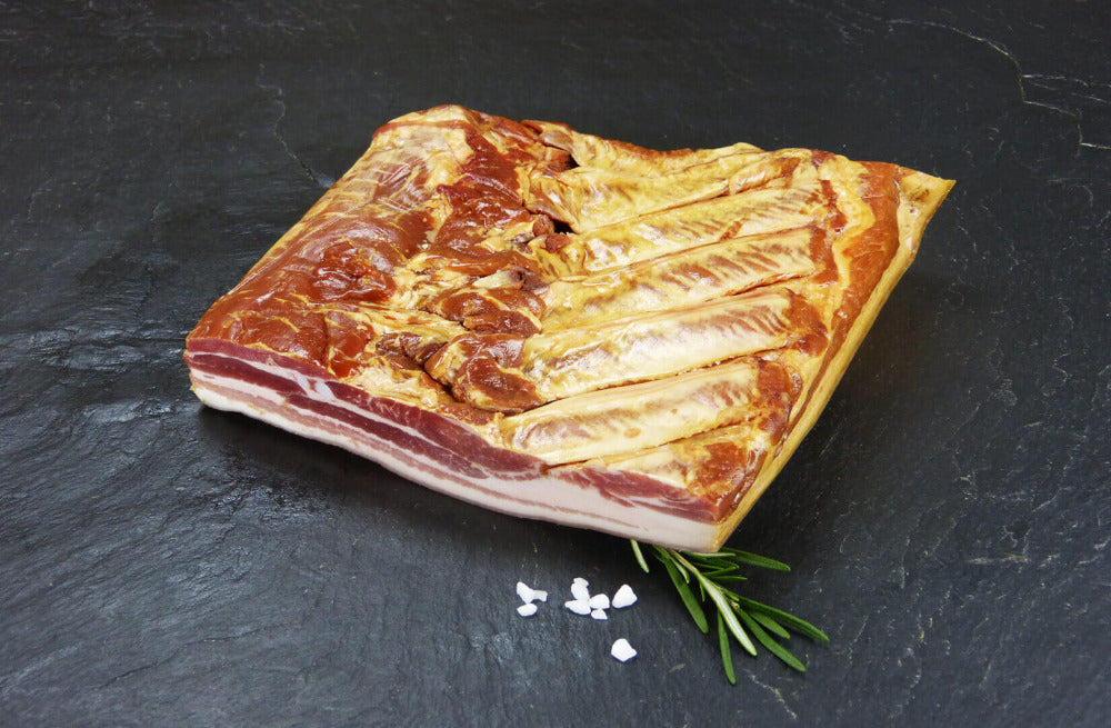 Dörrfleisch trocken gesalzen mit grobem Salz und Rosmarin auf Schieferhintergrund