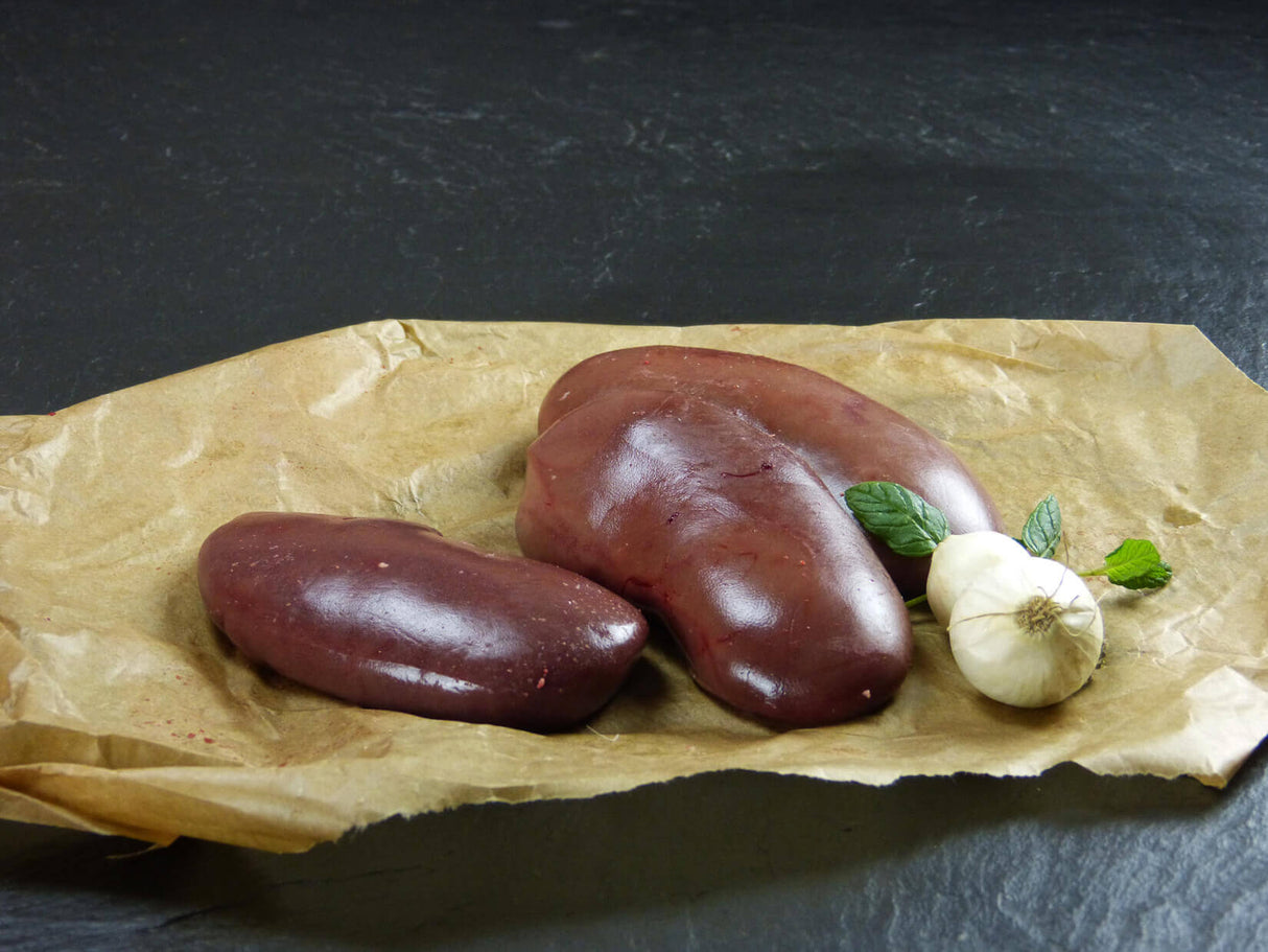 Schweinenieren mit Knoblauch und Basilikum auf Schieferhintergrund