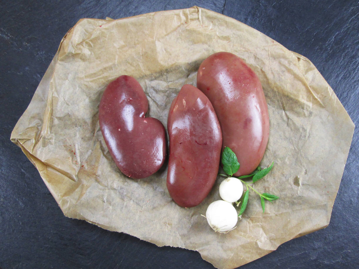 Schweinenieren mit Knoblauch und Basilikum auf Schieferhintegrund von oben fortografiert