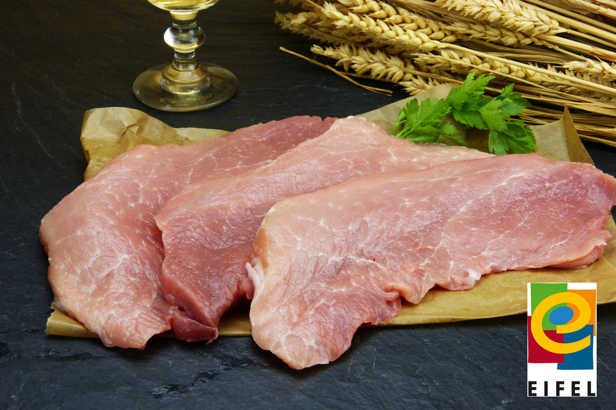 Oberschalenschnitzel vom EIFEL Schwein mit glatter Petersilien und Ähren auf Schieferrhintergrund
