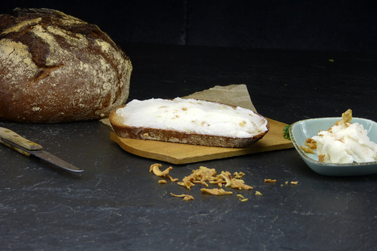 Griebenschmalz vom EIFEL Schwein angerichtet auf Brotscheibe auf Holzbrett im Schieferhintergrund