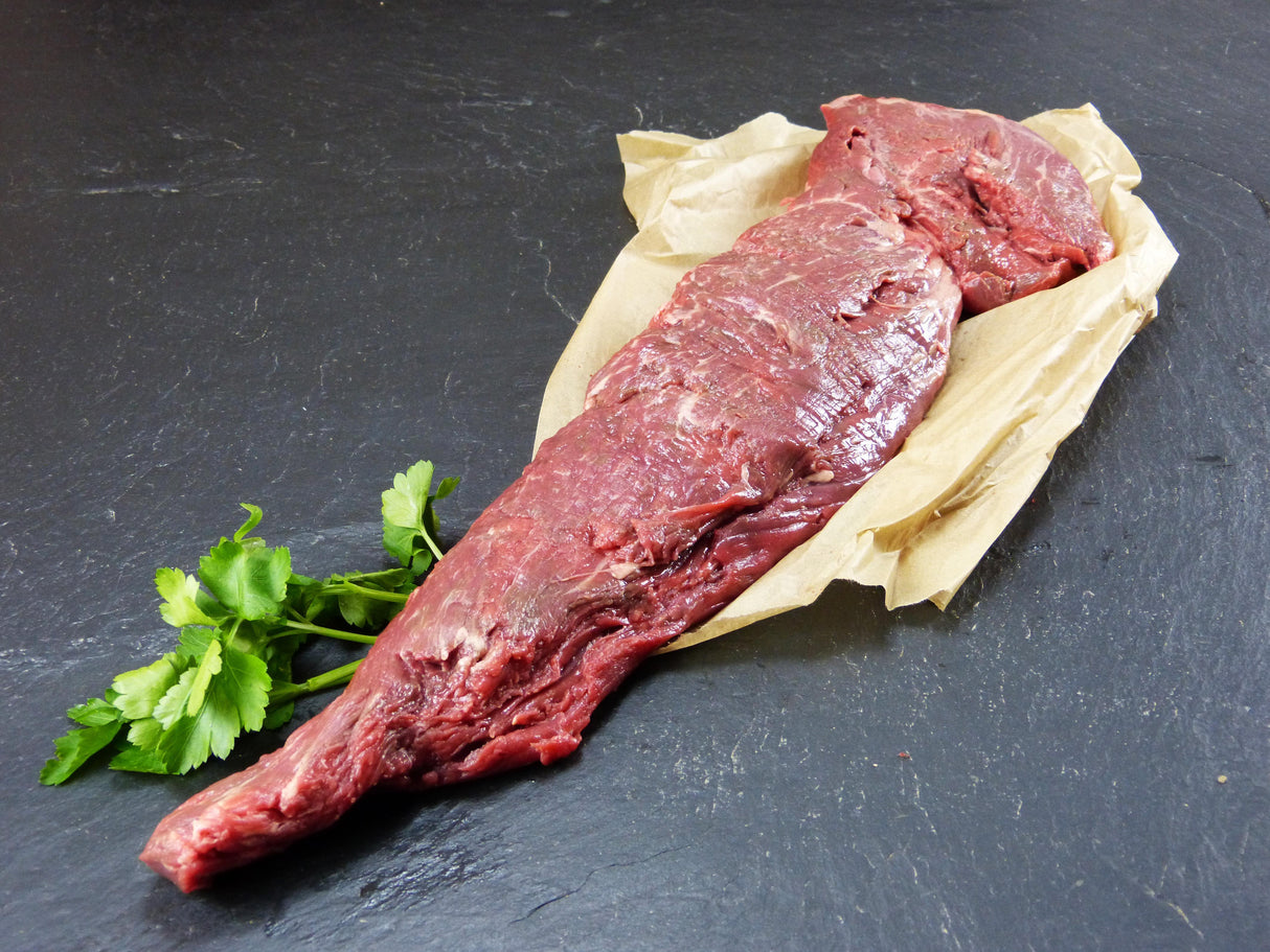 Argentinisches Rinderfilet auf Backpapier und Kräutern auf Schieferhintergrund