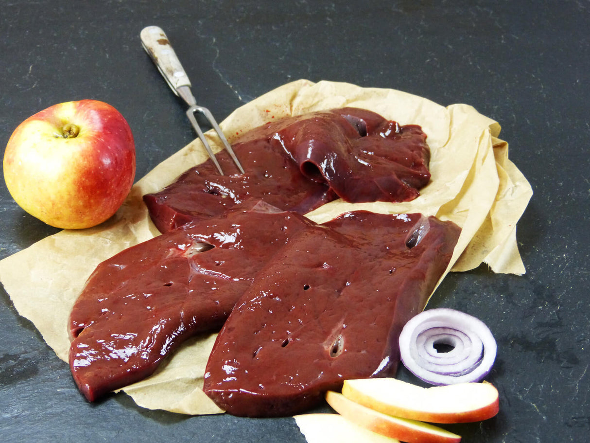 Rinderleber geschnitten mit Apfel und Zwiebel auf Schieferhintergrund