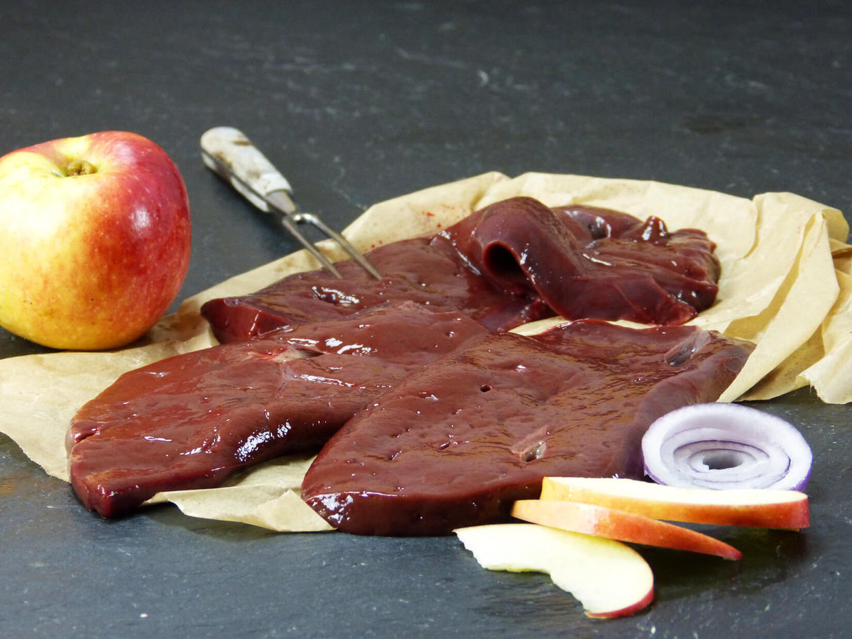 Rinderleber geschnitten mit Apfel und Zwiebel auf Schieferhintergrund