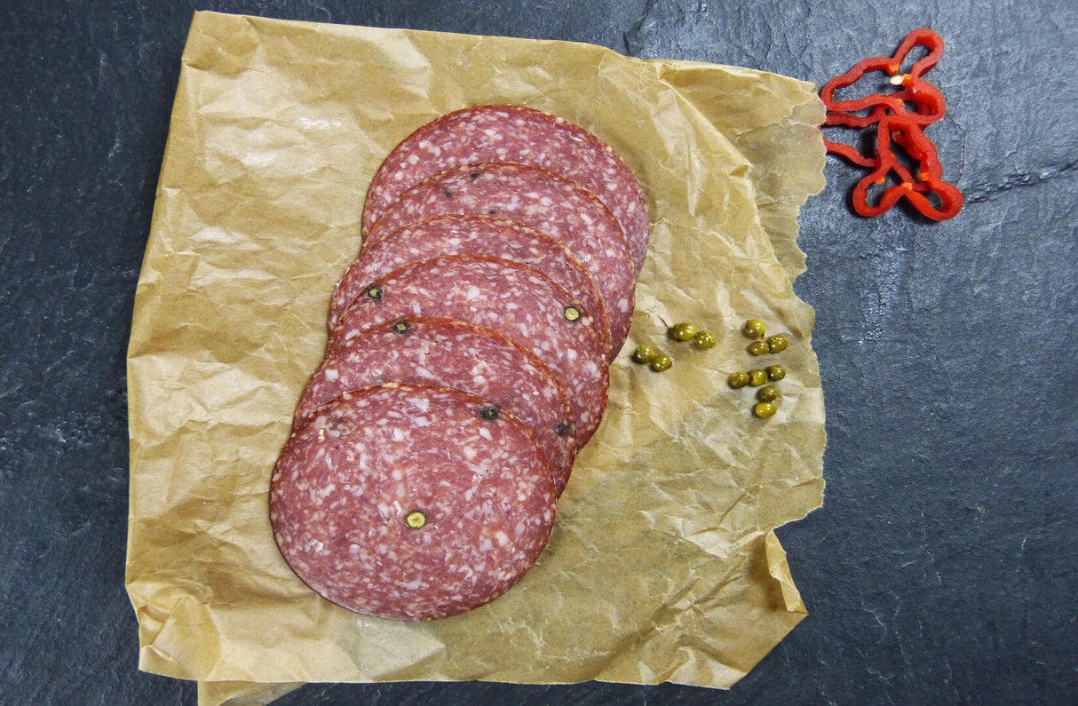 Pfeffersalami geschnitten mit Pfeffer und Paprika auf Schieferhintergrund