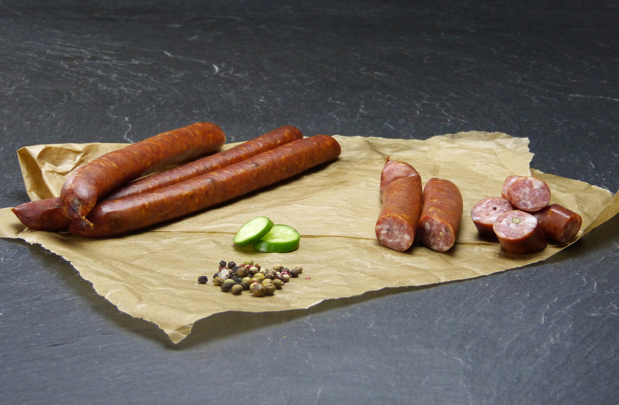 Pfeffer Schinkenmettwurst vom EIFEL Schwein mit Pfefferkörner und Gurke auf Schieferhintergrund