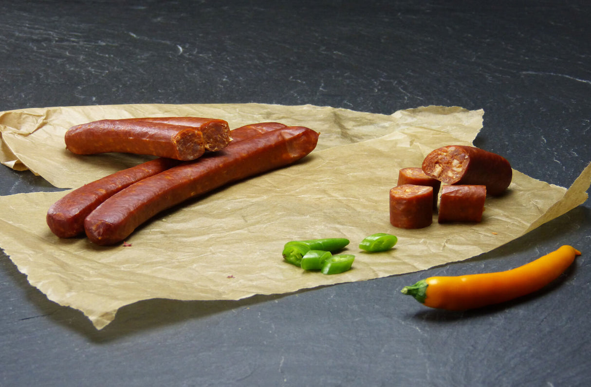 Chili Schinkenmettwurst vom EIFEL Schwein mit Chilischoten auf Schieferhintergrund