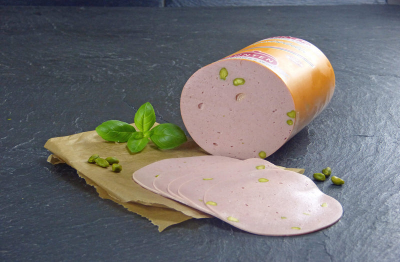 Mortadella vom EIFEL Schwein geschnitten mit Basilikum und Pistazien auf Schieferhintergrund