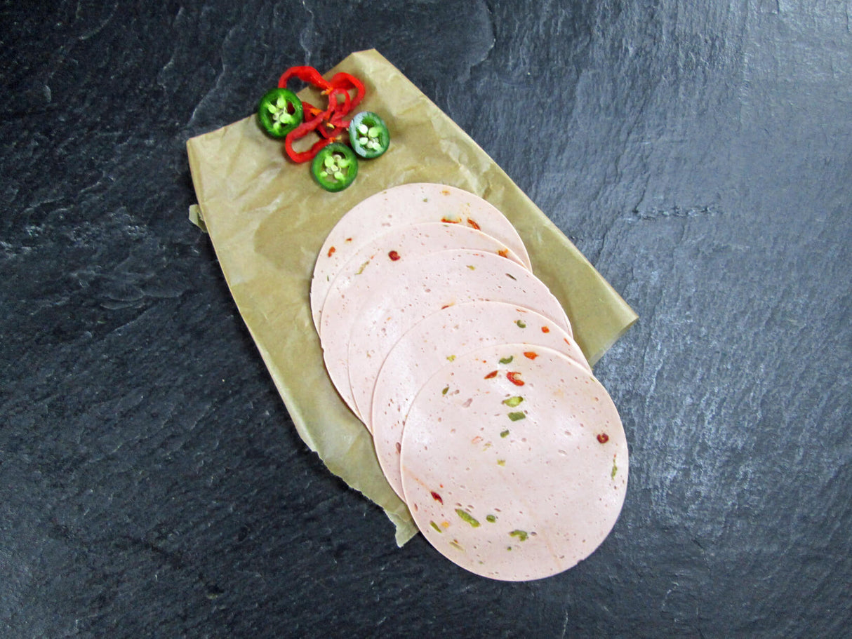 Paprikawurst Aufschnitt geschnitten mit Paprika und Peperonischeiben auf Schieferhintergrund