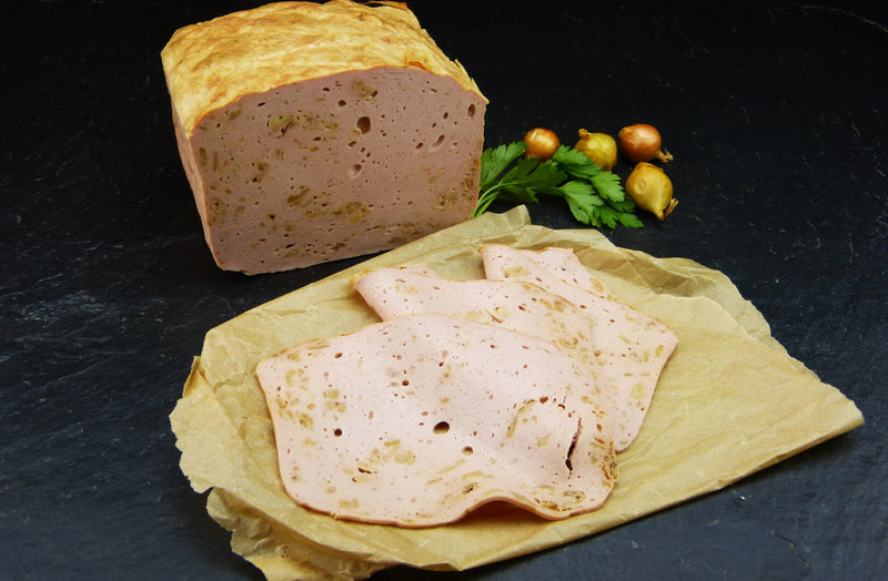 Zwiebelfleischkäse gebacken geschnitten vom EIFEL Schwein mit Petersilie und Zwiebeln auf Schieferhintergrund