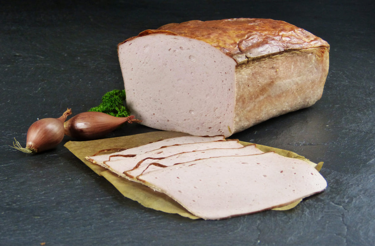 Fleischkäse gebacken geschnitten vom EIFEL Schwein mit Zwiebeln und Petersilie auf Schieferhintergrund