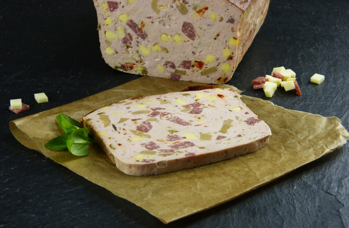 Pizzafleischkäse gebacken Riegel vom EIFEL Schwein mit Basilikum Käsewürfeln und Salamiwürfeln auf Schieferhintergrund