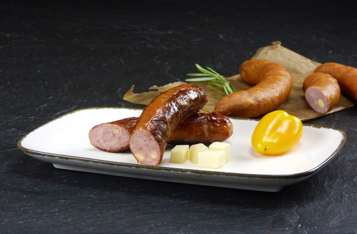 Käsebrater vom EIFEL Schwein mit Rosmarin Käsewürfeln und einer gelben Paprika auf Schieferhintergrund