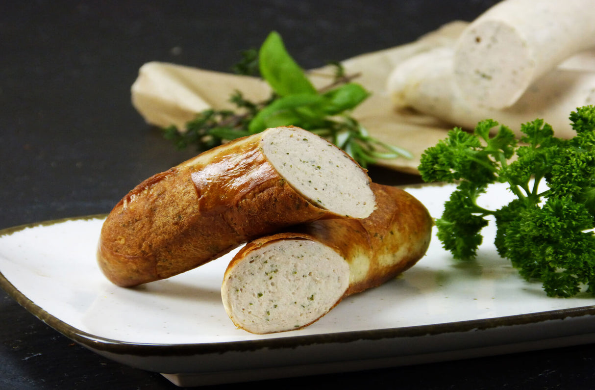 Jubiläumsbratwurst mit Basilikum Rosmarin und Petersilie auf Schieferhintergrund
