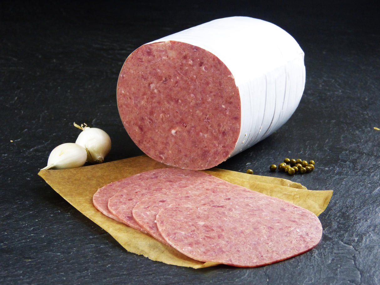 Deutsches Cornedbeef geschnitten mit Knoblauch und Pefferkörner auf Schieferhintergrund