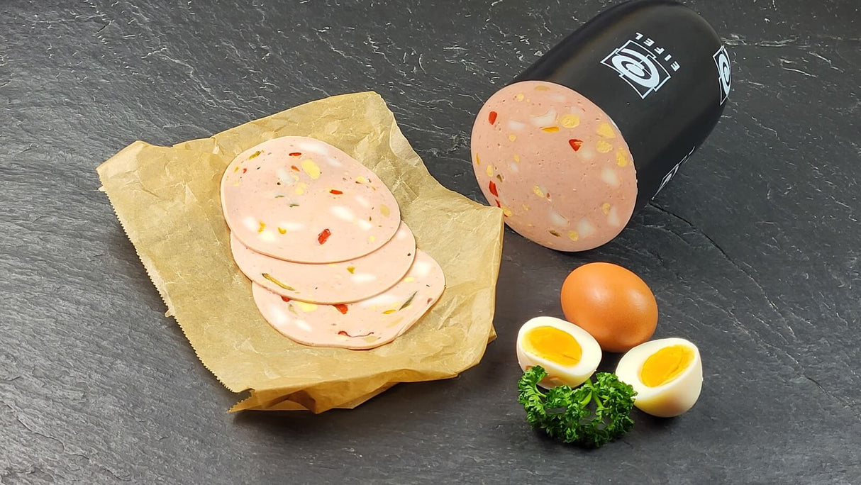 Eierlyoner mit Paprika vom EIFEL Schwein geschnitten neben Petersilie und Eiern auf Schieferhintergrund