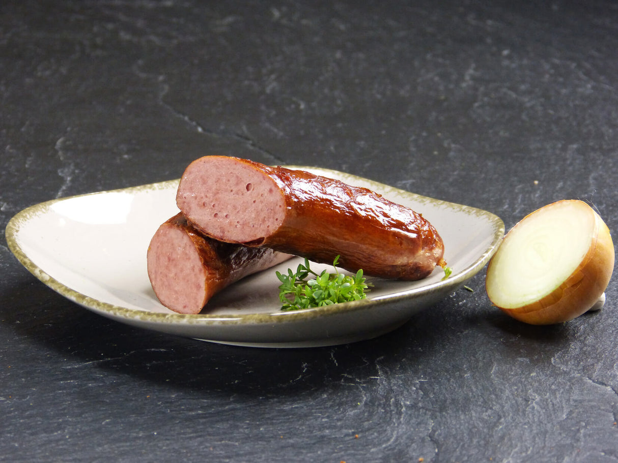 Rindswürstchen vom EIFEL Rind mit Petersilie und einer halben Zwiebel auf Schieferhintergrund