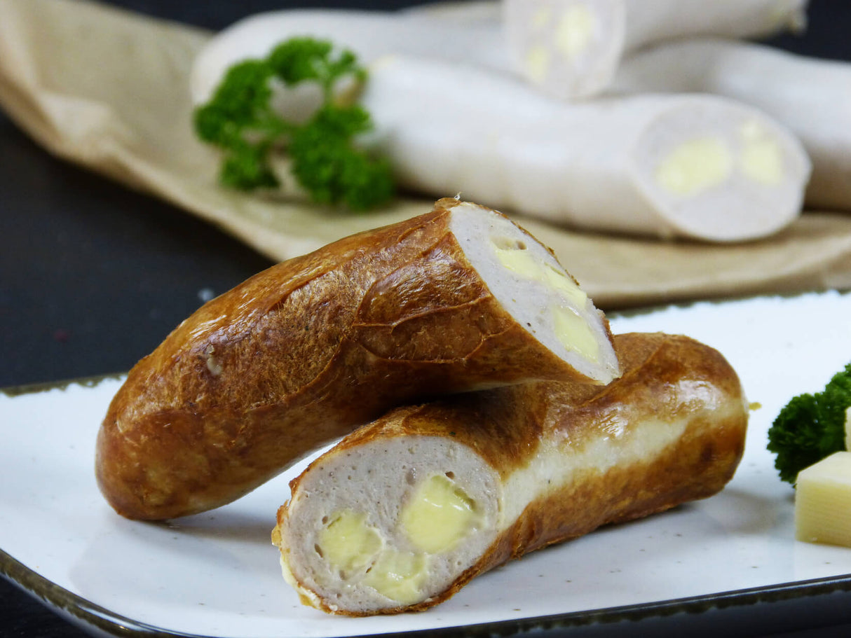 Käsebratwurst vom EIFEL Schwein mit Petersilie und Käsewürfeln auf Schieferhintergrund