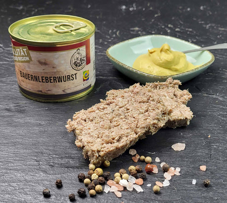 Bauernleberwurst 200g Dose vom EIFEL Schwein angerichtet mit groben Salz und Pfefferkörnern und einer kleinen Schale Senf auf Schieferhintergrund