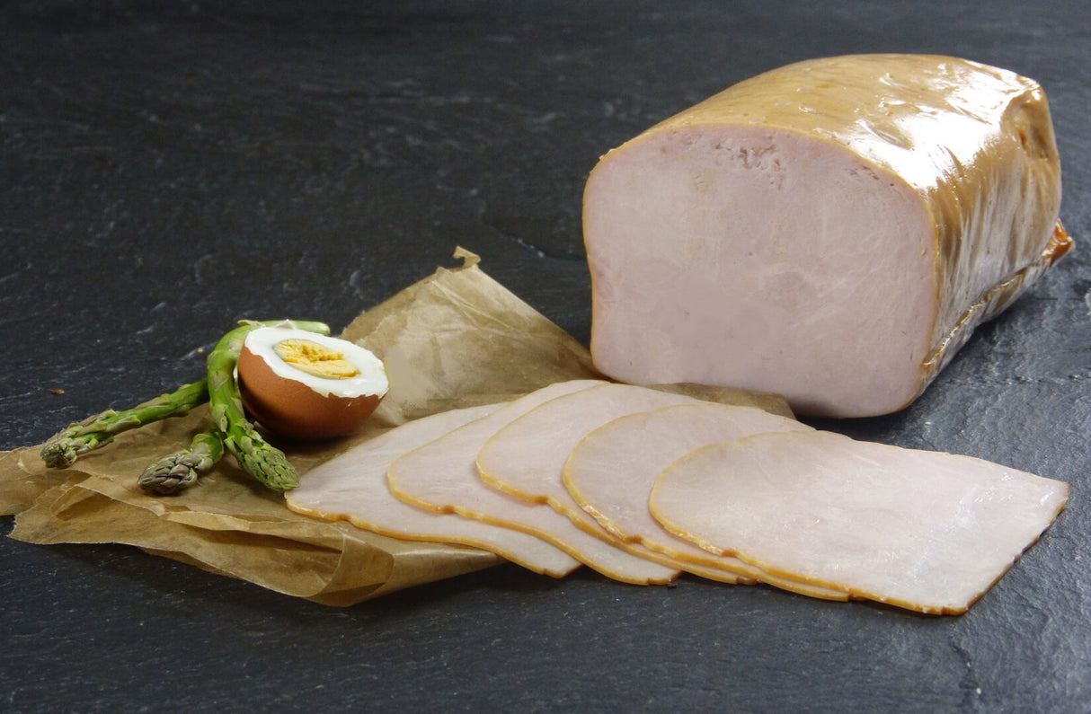 Putenbrust geräuchert geschnitten mit einem halben Ei und Spargel auf Schieferhintergrund