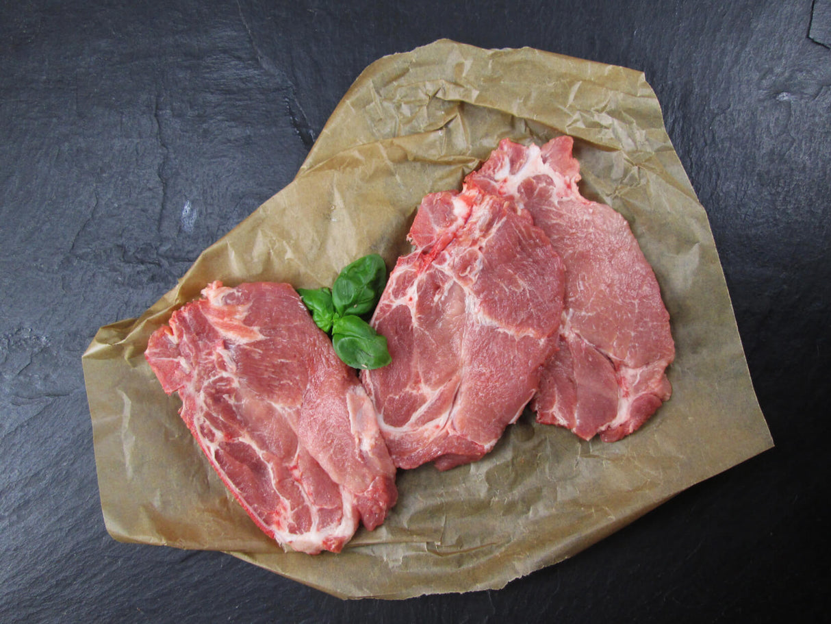 Kammkotelett mit Basilikum auf Schieferhintergrund