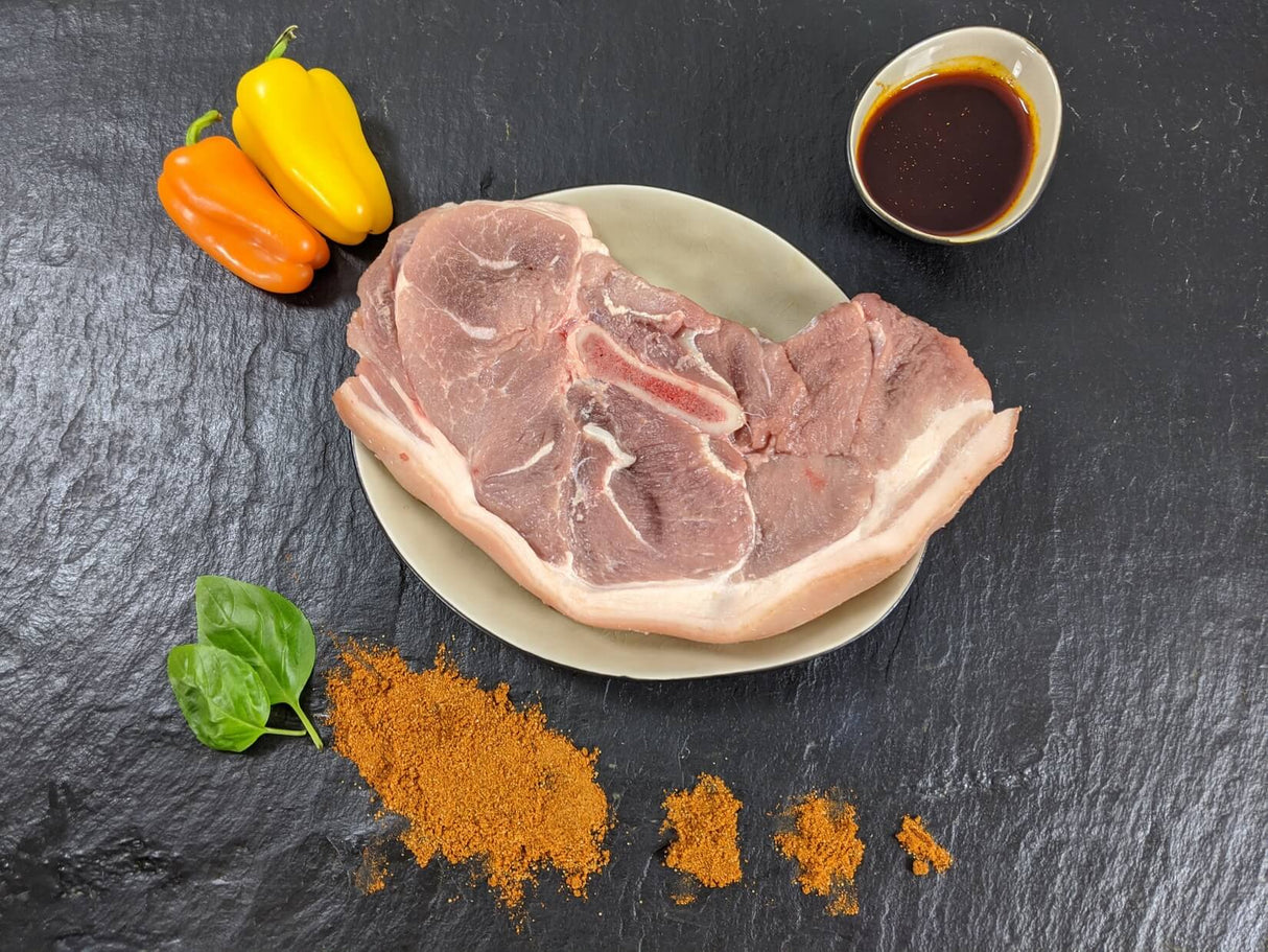 Holzfällersteak Paprika auf Teller angerichtet mit einer Schale Marinade Paprika Kräutern und Paprikapulver auf Schieferhintergrund