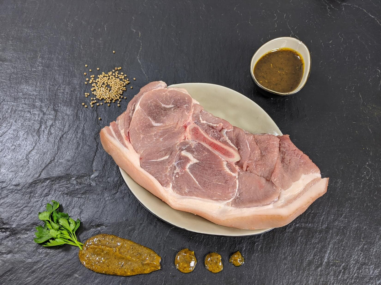 Holzfällersteak Senfzauber auf Teller angerichtet mit einer Schale Marinade Senfkörnern und Kräutern auf Schieferhintergrund