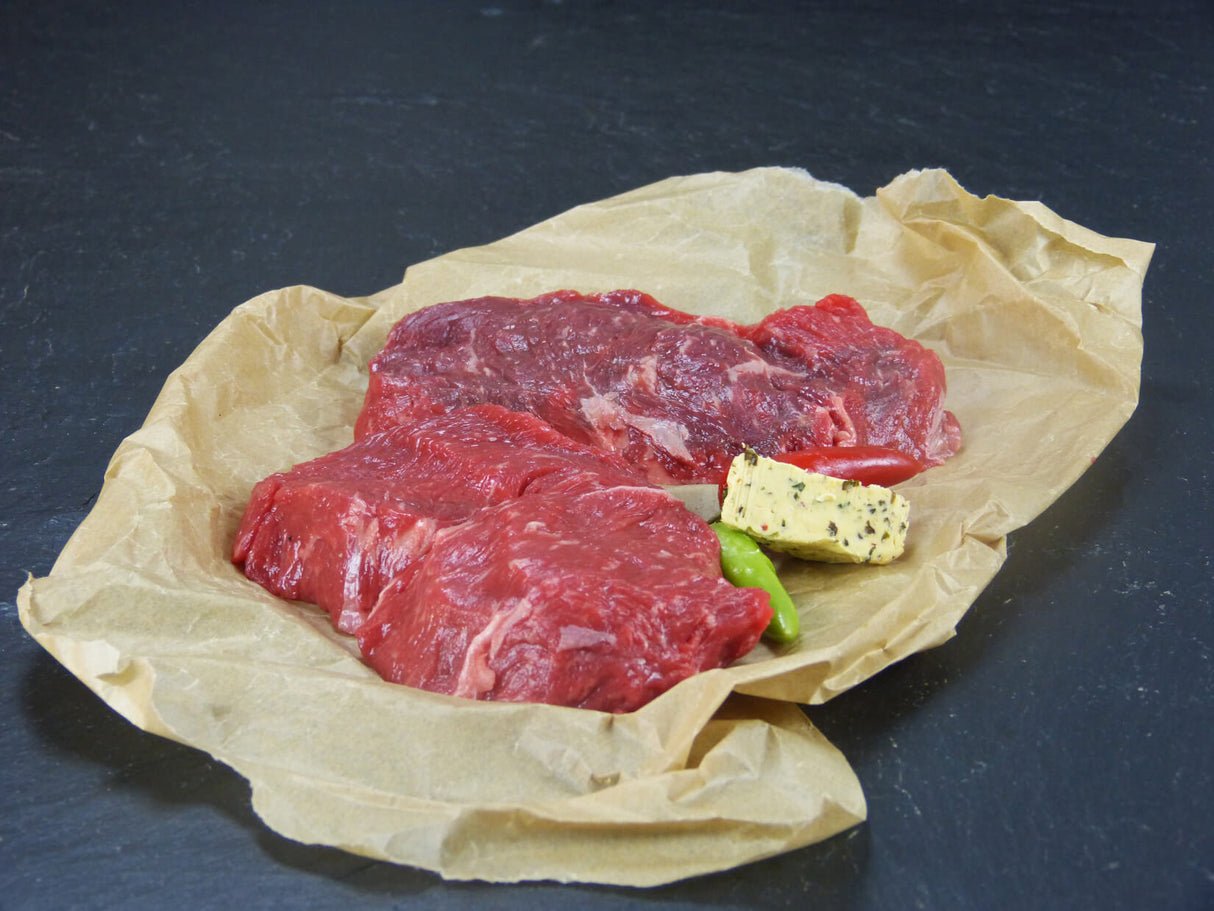 Argentinisches Rumpsteak mit Kräuterbutter und Peperoni auf Schieferhintergrund