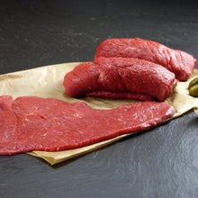 Rinder Rouladen aus der Oberschale auf Backpapier angerichtet mit Essiggurken und Silberzwiebeln auf Schieferhintergrund