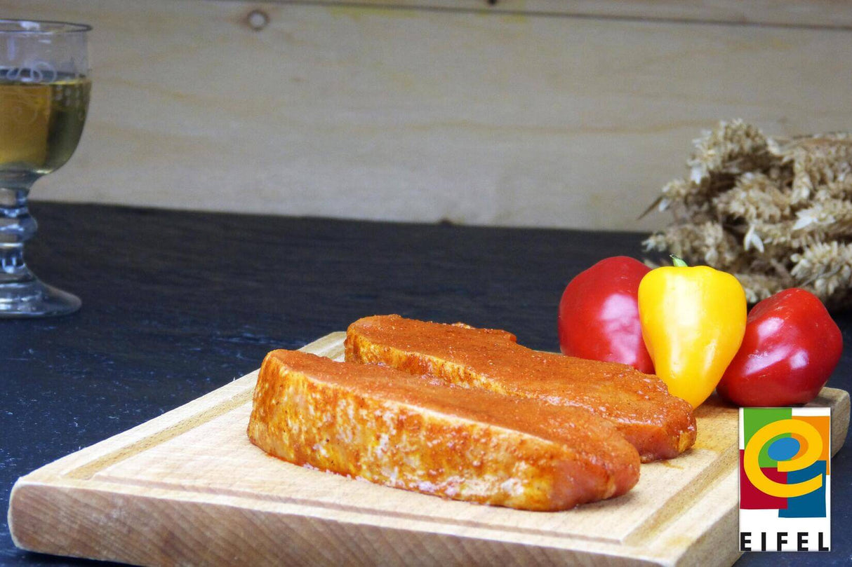 Rückensteak Paprika vom EIFEL Schwein auf Holzbrett mit Paprika auf Schieferhintergrund