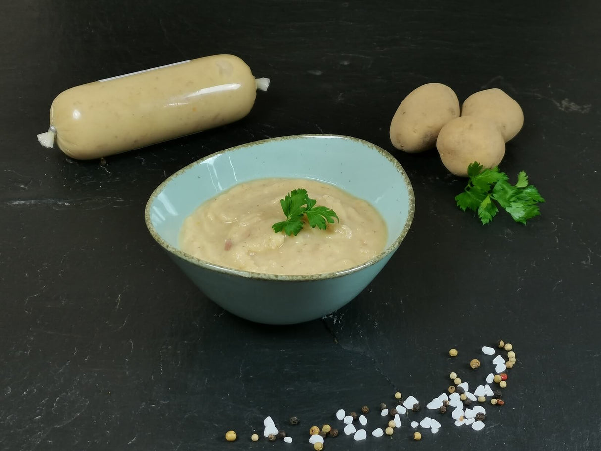 Kartoffelsuppe in Schale angerichtet mit Petersilie und Kartoffeln auf Schieferhintergrund