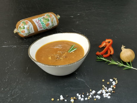 Gulaschsuppe in Schale angerichtet mit Paprika Zwiebel und Rosmarin auf Schieferhintergrund