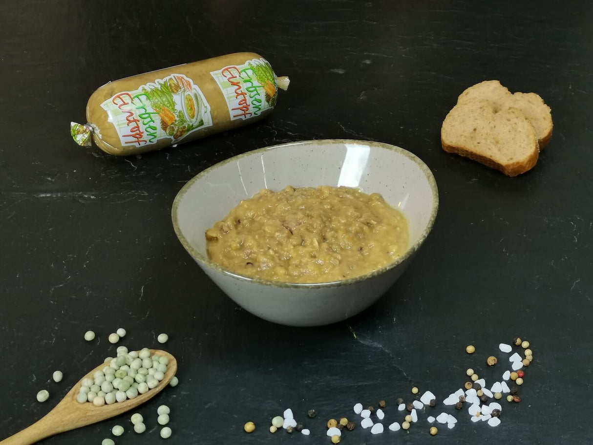 Erbsensuppe in Schale angerichtet mit Brot auf Schieferhintergrund