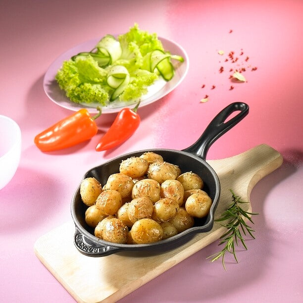 Country Kartöffelchen mit Salat und Paprika auf Holzbrett vor rötlichem Hintergrund