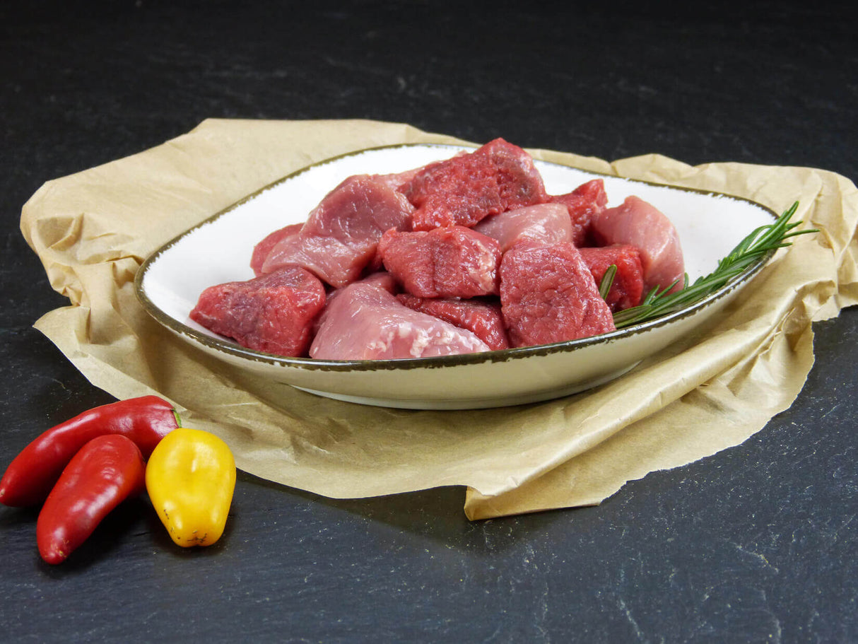 Gulasch gemischt in einer Schüssel mit Rosmarin und Paprika auf Schieferhintergrund