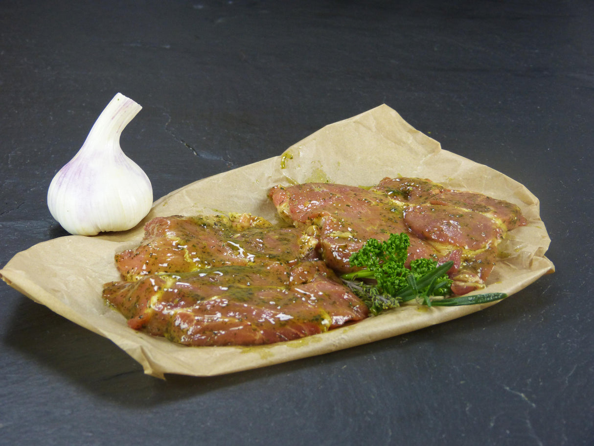 Schweinenackensteak Kräuter Knoblauch mit Petersilie und Knoblauch auf Schieferhintergrund