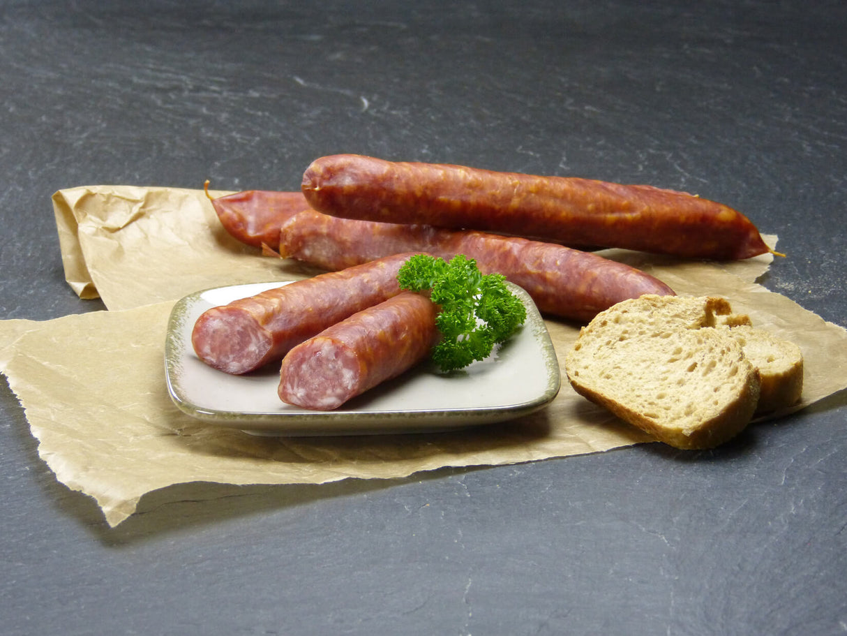 Grobe Mettwurst vom EIFEL Schwein mit Baguettebrot und Petersilie auf Schieferhintergrund