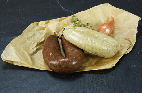 Unser Küsschen je 1 Bauernleber und Blutwurst vom EIFEL Schwein angerichtet auf Backpapier mit einer kleinen Zwiebel und Kräutern auf Schieferhintergrund