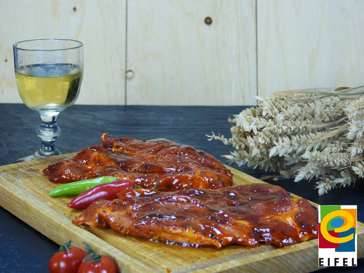 Kammsteak Barbecue vom EIFEL Schwein auf Holzbrett angerichtet mit Chilischoten auf Schieferhintergrund