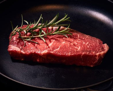 Rohes Roastbeef mit Rosmarin in schwarzer Pfanne als Merkmal für gutes Fleisch