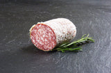 Mailänder Salami am Stück mit Thymian auf Schieferhintergrund
