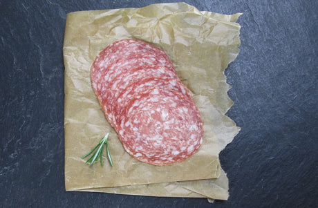 Mailänder Salami geschnitten angerichtet mit Thymian auf Backpapier mit Schieferhintergrund