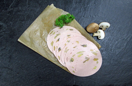 Fünf scheiben Champignon Lyoner vom EIFEL Schwein angerichtet mit Champignonpilzen und Petersilie auf Backpapier mit Schieferhintergrund