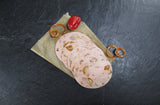 Fünf Scheiben Spießbratenwurst vom EIFEL Schwein angerichtet mit einer kleinen Paprika und paar Zwiebelringen mit Paprika gewürz drauf auf Backpapier mit Schieferhintergrund
